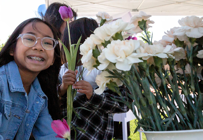 young girl with braces smiling next to a bucket with fresh cut white flowers