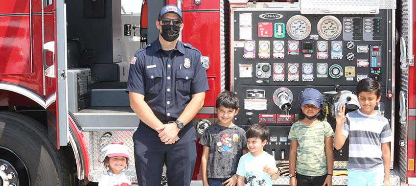 Firefighter taking picture with kids in front of the firetruck